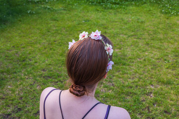 Young girl with hair decoration looking at green grass lawn. Sweden.