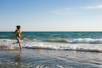 A woman in a bathing suit rests on the sandy seashore and bathes in the waves