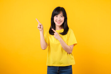 Confident Asian woman pointing to free copy space isolated on yellow studio background