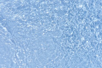 Naklejka premium Blue water with ripples on the surface. Defocus blurred transparent blue colored clear calm water surface texture with splashes and bubbles. Water waves with shining pattern texture background.