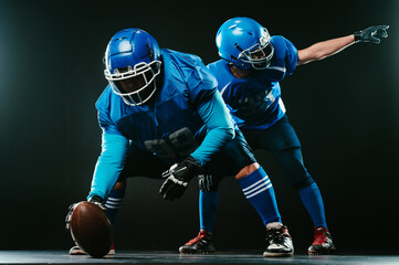 Two American football players are ready to start the game on a black background. 