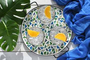 Spa water with orange slices or mixed drinks cocktails sea glass mosaic tile tray tropical greenery