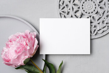 Wedding invitation or greeting card mockup with fresh flower over grey