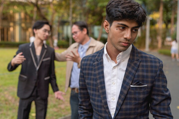 A man walks away after seeing his boss giving preferential treatment to his co-worker while outside. Feeling depressed or jealous. Favoritism and discrimination in the workplace.