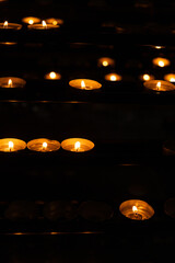 A lot of burning candles in the temple in the dark. The concept of religion, prayer and God.