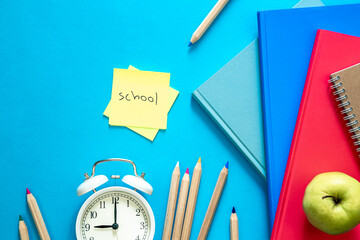 Flat lay composition with colorful educational supplies on blue background.