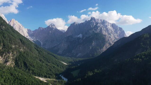 Aerial shot top view of Rocky Mountains. Sunny wether High hills on background . Green forest and valley.