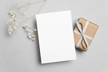 Blank greeting card mockup with gift box and flowers decor