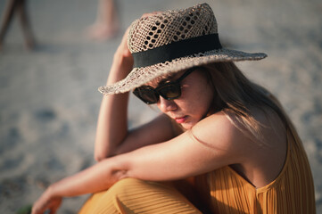 young woman sitting on the beach and watching the sunset