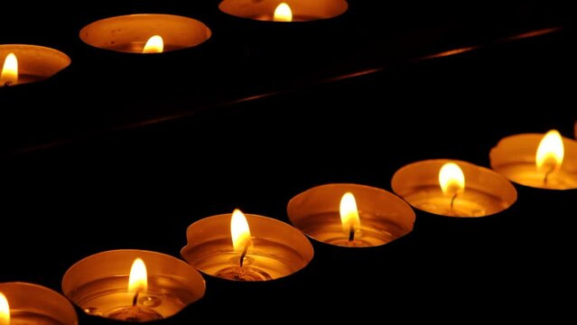 A lot of burning candles in the temple in the dark. The concept of religion, prayer and God.