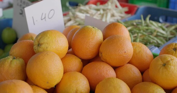 A close-up of an orange on a seller's display at the market. Fresh fruit from farm gardens sold at the bazaar. High quality 4k footage
