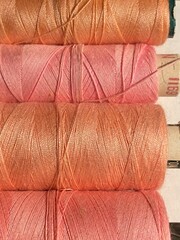 Fototapeta na wymiar cotton thread reels bobbin fuchsia pink and peach orange background with copy space