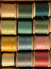 cotton thread reels bobbin fuchsia pink and teal cyan blue on duck egg blue background with copy space