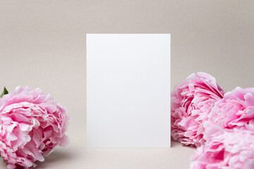 Invitation or greeting card mockup with fresh peony flowers, blank card with copy space