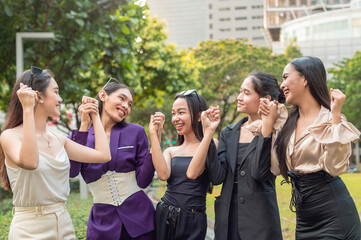 5 asian women looking at each other, holding hands together and wishing for success. Five friends united together.