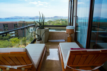 Two deckchairs in hotel room balcony by swimming pool, seascape and mountain in the background at Costa Rica