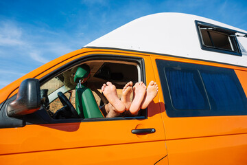Crop person with legs stretched out from camper van window
