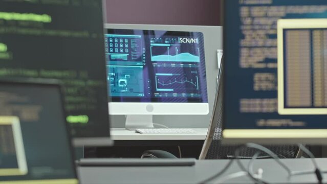 Zoom in no people shot of office desks with three desktop computers demonstrating sophisticated program codes and monitoring data protection system in cyber security agency
