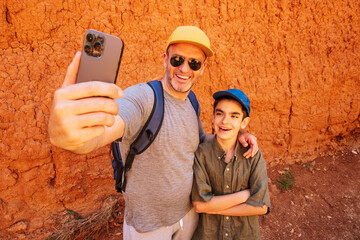 Cheerful father and son taking selfie on smartphone