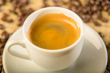 Close up of a cup of expresso coffee with roasted beans 