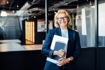 Happy smiling 50's confident mature businesswoman looking at camera, middle-aged experienced senior female professional hired by company on first day at work, happy new employee on office background