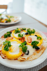 Fresh homemade breakfast pizza on bread wrap with eggs, cheese, tomatoes, bell pepper and herbs on the served table. Tasty and healthy ideas for breakfast at home. Vertical card. Soft selective focus.