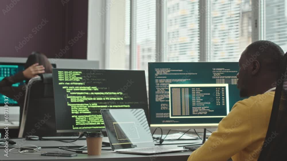 Wall mural back view of multiethnic couple of software developers program coding and monitoring information on 