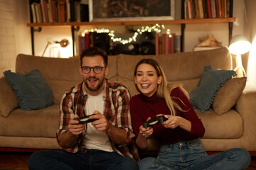 Plakat Young couple having fun at home playing video games