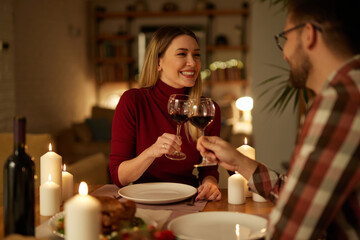 Beautiful couple having romantic dinner with candles and red wine at home