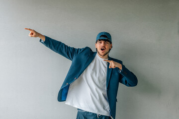urban young man in cap or student celebrating excited with wall in background