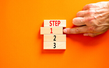 Time to step 1 symbol. Concept word Step 1 2 3 on wooden block. Businessman hand. Beautiful orange table orange background. Business planning and time to step 1 concept. Copy space.