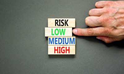 Time to low risk symbol. Concept word Risk low medium high on wooden block. Businessman hand. Beautiful grey table grey background. Business time to low risk concept. Copy space.