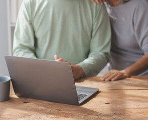 Embraced mature couple surfing the Internet on laptop at home