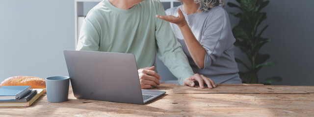 Embraced mature couple surfing the Internet on laptop at home