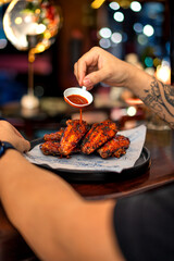 Close up shot of a hand eating bbq wings at a bar