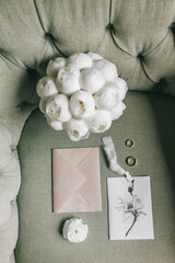 Wedding rings, wedding invitations, a bouquet of white peonies. Wedding day details.