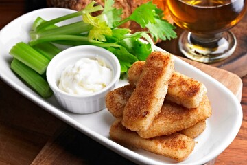 Close-Up of Crispy Fried Fish Sticks with Celery on Plate in 4K Resolution