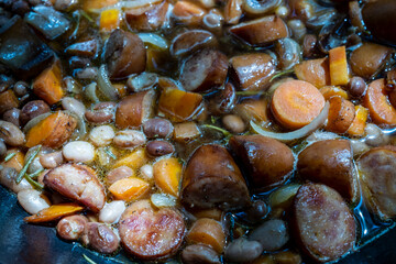 beans and sausage are cooked in a large cast iron pot