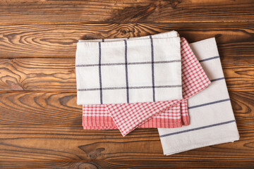 Kitchen towels on a brown wooden background. New kitchen cotton towels on the kitchen table. A set of towels. Home textiles. Place for text. copy space.