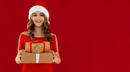 young smiling happy pretty woman holding present boxes celebrating new year, christmas gifts, wearing red dress, posing on red background