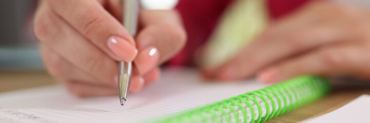 Female hand holding pen and write something in notepad