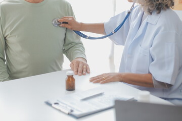 Mature Asian male doctor talking with his patient, explaining the procedure to old lady.