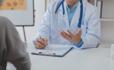 Mature Asian male doctor talking with his patient, explaining the procedure to old lady.