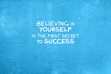 Blue concrete wall with inspirational quotes - Believing in yourself is the first secret to success