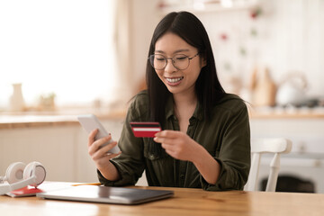 Positive asian woman freelancer banking or shopping from home