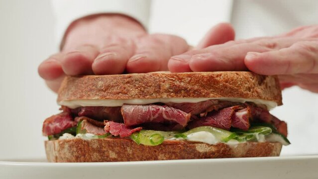 American pastrami sandwich in New York ham meet cuts. chef cooking Famous thick cut sous vide beef sandwich on restaurant cafe kitchen.