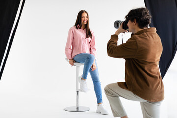 Fototapeta na wymiar Stylish photoshoot. Male fashion photographer taking picture of young european woman in casual wear