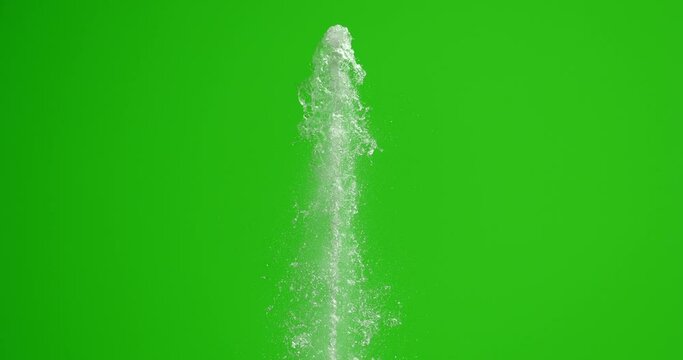 The stream of water hits the top with force. Splashes of water on a green background. The fountain rises.