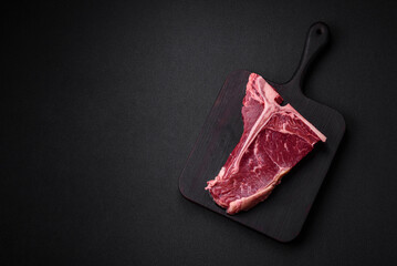 Raw juicy beef t-bone steak with salt, spices and herbs