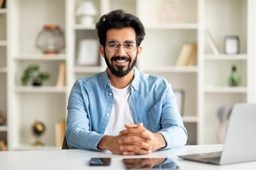 Obraz premium Millennial Freelancer. Indian Man Sitting At Desk With Laptop In Home Office,